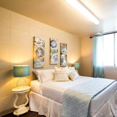 A bedroom with a bed, a nightstand with a lamp, and a window with curtains.