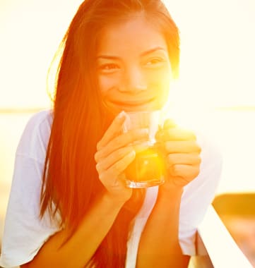 a woman holding a glass of orange juice