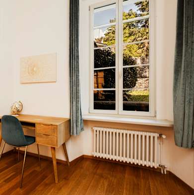 a corner of a room with a desk and a window