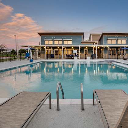 A large swimming pool in front of a building with a sunset in the background.