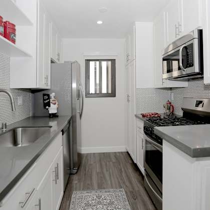 a renovated kitchen with white cabinets and stainless steel appliances