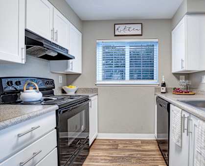 A kitchen with white cabinets and a black stove top.