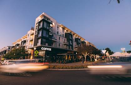A coffee shop is located in a modern building with a black awning.