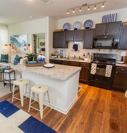 A kitchen with a white island and dark cabinets.