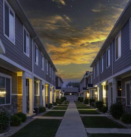 a row of town homes at night with the sun setting behind them