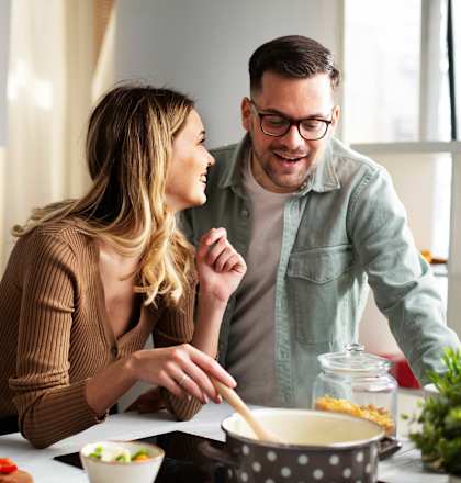A man and a woman are cooking together in a kitchen.