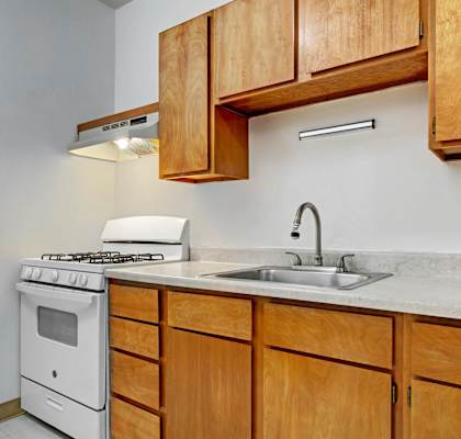 A kitchen with a white stove and wooden cabinets.
