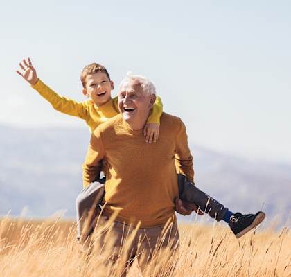 an elderly man and a young boy playing in a grassy field