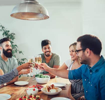 A group of people are toasting with glasses of wine at a dinner table.