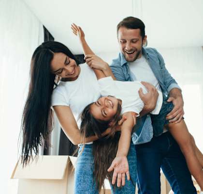 A man lifts a woman into the air while another woman looks on.