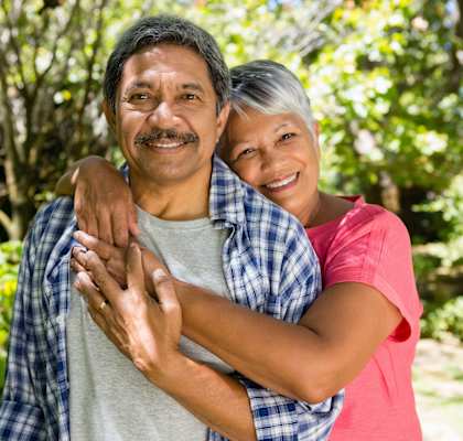 A man and woman are hugging each other in a garden.