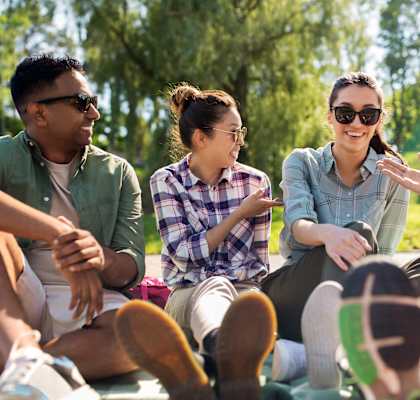 Four people sitting on a blanket in a park at Ridge Crossings Apartments, Alabama 35244