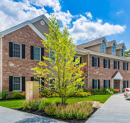 a large brick building with a tree in front of it at Greenway Village Apartments, Metuchen, New Jersey