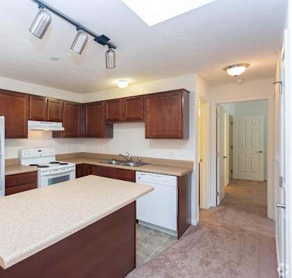 A kitchen with brown cabinets and a white fridge.
