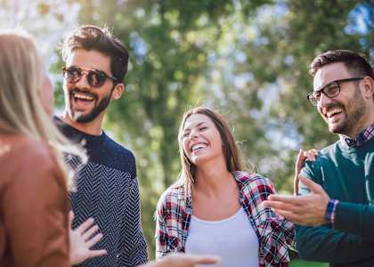 Four people are standing outdoors and laughing together.