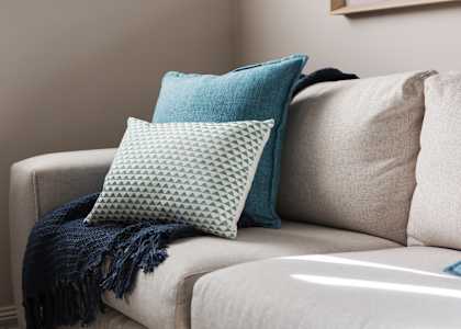 A couch with a blue pillow and a blue blanket on it.