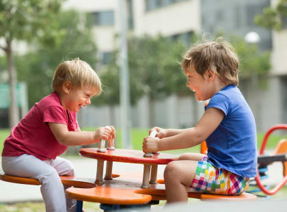 two children playing on a table in a park
