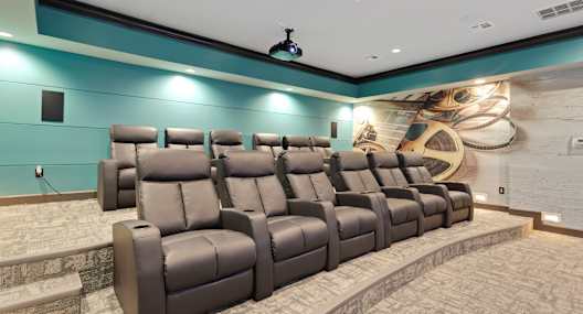 A row of brown leather reclining chairs are arranged in a semi-circle in front of a wall with a large mural.