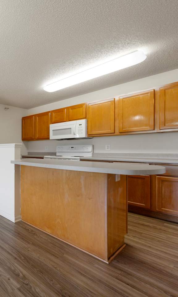 A kitchen with wooden cabinets and a white microwave.