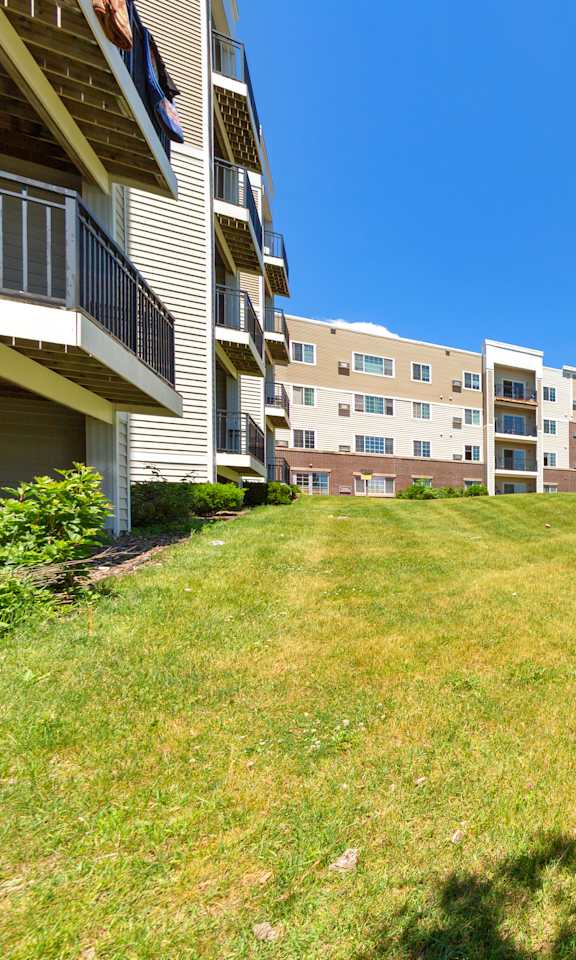 A sunny day at a grassy area in front of apartment buildings.