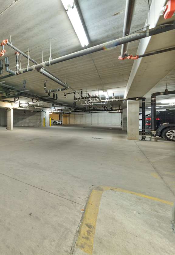 A parking garage with two cars parked inside.