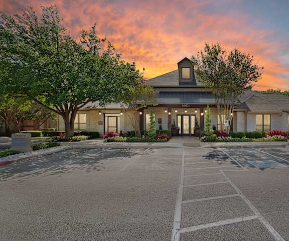 a parking lot in front of a building with trees at Sonterra Apartment Homes, Austin, TX