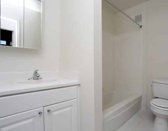 A white bathroom with a toilet, sink, and bathtub.