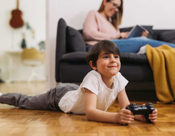 a little boy laying on the floor holding a video game controller