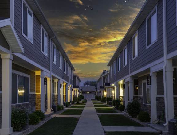 a row of town homes at night with the sun setting behind them