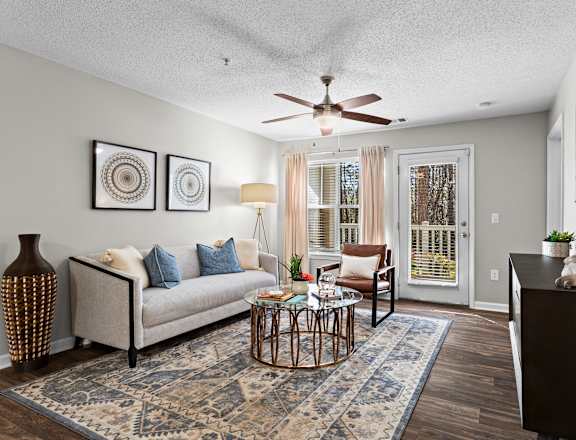 A living room with a couch, a coffee table, and a ceiling fan.