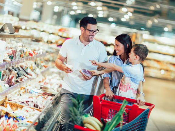 A man and a woman with a child are shopping in a grocery store. at Dolce Villagio Townhomes, Tempe, 85281