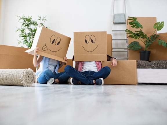 two people sitting on the floor holding boxes with smileys on their faces