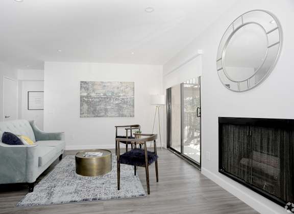 a living room with a couch and a fireplace and a round mirror