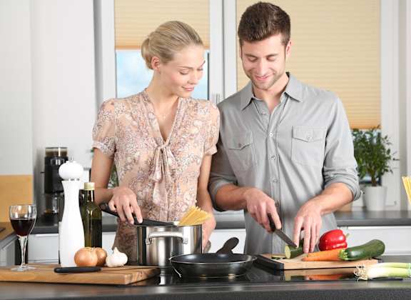 A man and woman are cooking together in a kitchen.