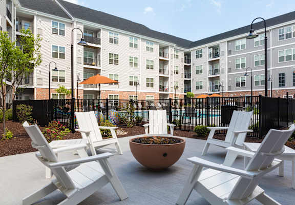 A patio with white chairs and a bowl in the middle.
