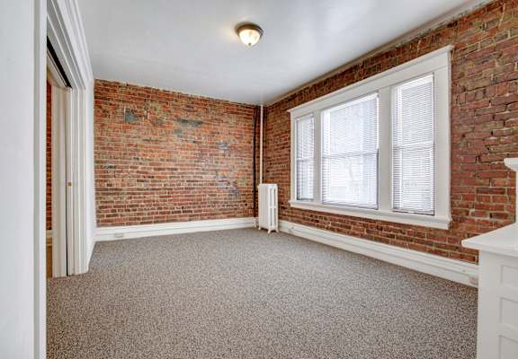 A room with a brick wall and a window.