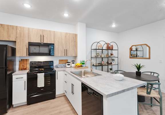 A modern kitchen with black appliances and wooden cabinets.