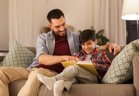 a man and a boy reading a book on a couch