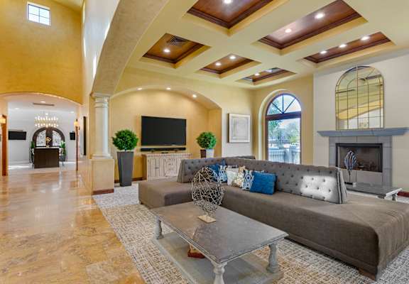 A living room with a grey couch and a fireplace.
