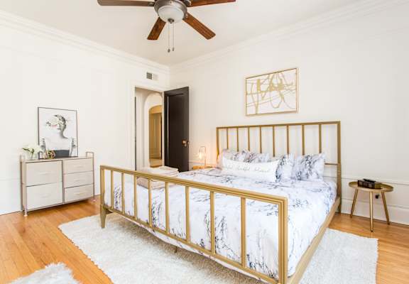 A bedroom with a bed, nightstand, and a ceiling fan.