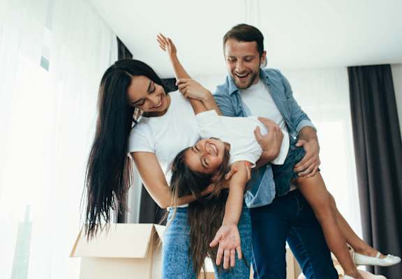 A man lifts a woman into the air while another woman looks on.
