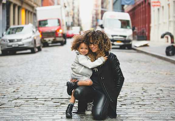 a woman hugging a child on a street