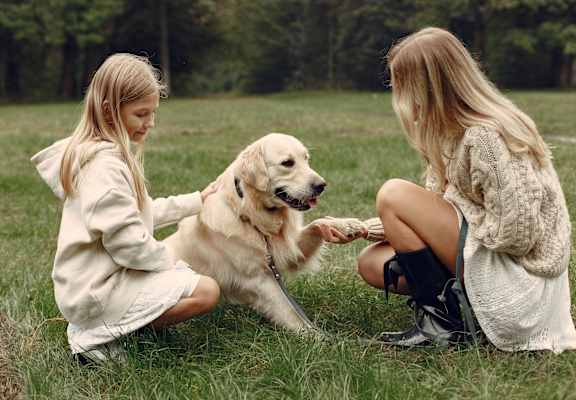 two girls playing with a dog in the grass at Terracina, Broomfield