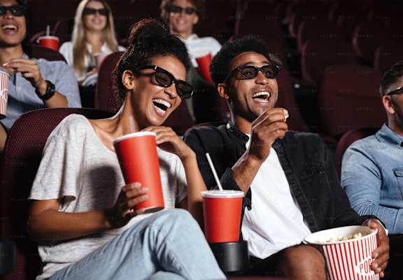 a group of people laughing and eating popcorn at a movie theater