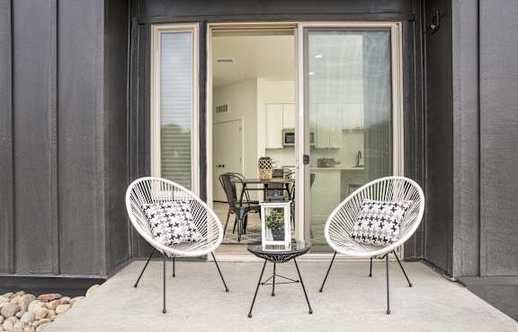 a patio with two chairs and a table and a sliding glass door