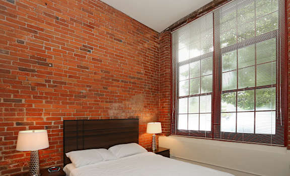 a bedroom with a bed next to a brick wall at Bigelow Commons, Enfield, 06082