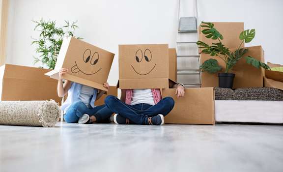 two people sitting on the floor holding boxes with smileys on their faces