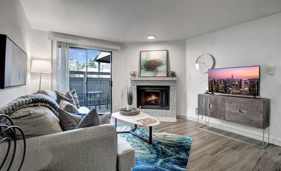 a living room with a fireplace and a sliding glass door to a balcony
