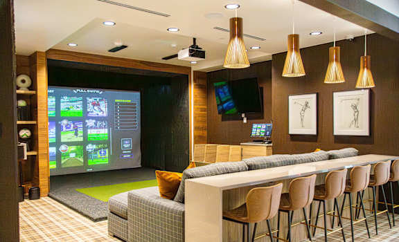 A modern bar with a large screen and comfortable seating.