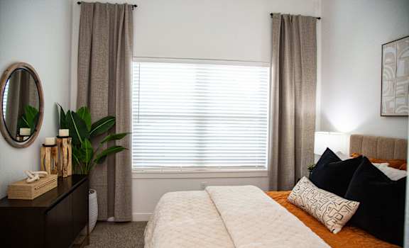 A bedroom with a large bed and a window with curtains.